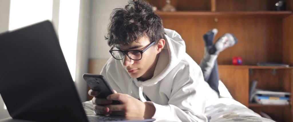 teen boy on phone and laptop