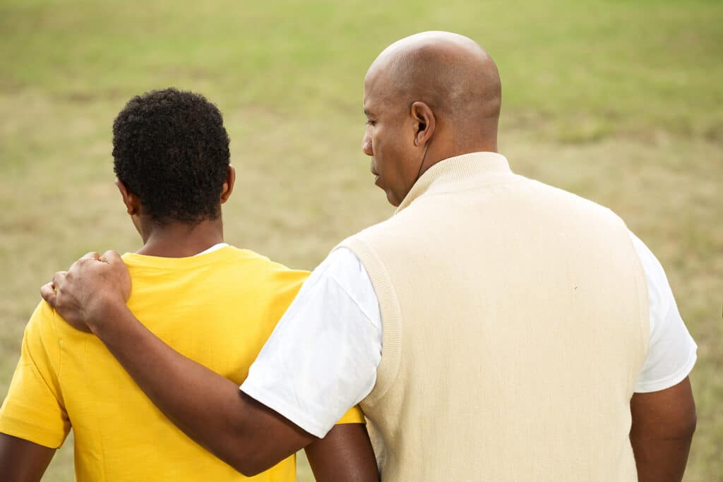 father with hand on son's shoulder