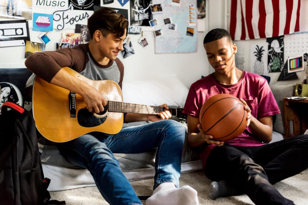 teen boys playing guitar and looking at basketball