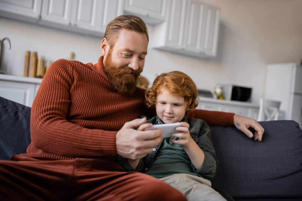 red headed father and son smiling at a phone