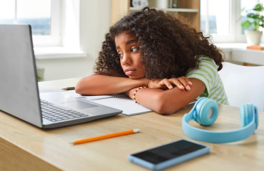 sad girl doing schoolwork in front of laptop