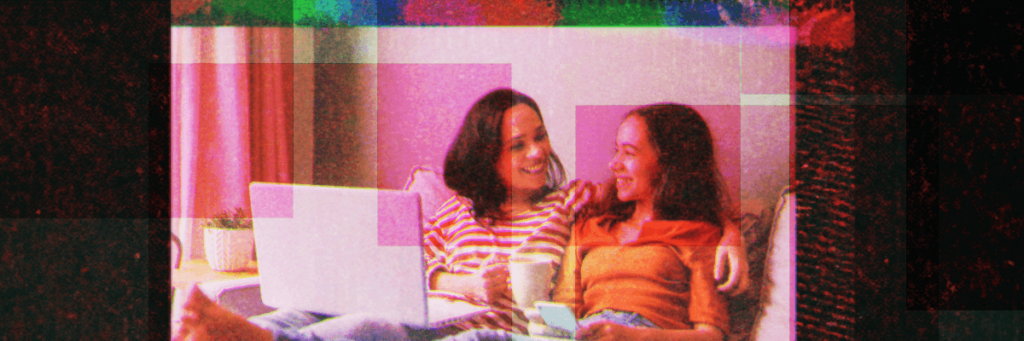 mom and daughter smiling at each other looking at laptop